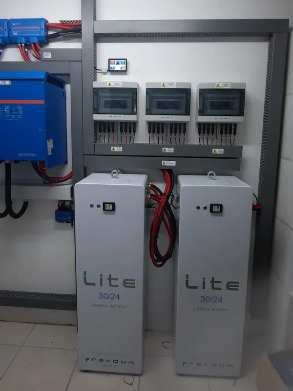Two Freedom Won LiTE 30/24 lithium iron phosphate batteries standing below three labelled surge protection boxes