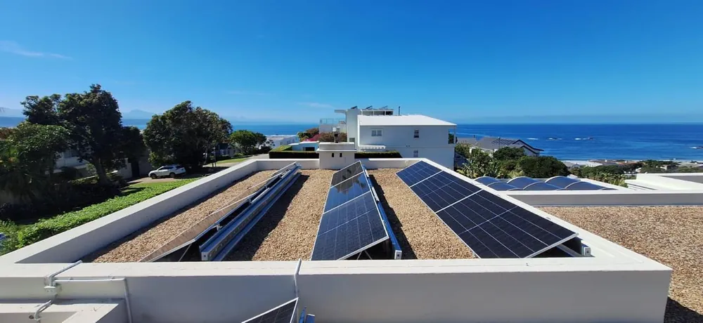 Rows of solar panels on a flat roof overlooking the ocean on the Garden Route coast