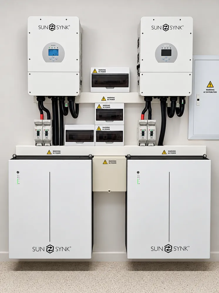 Two Sunsynk hybrid inverters mounted above two Sunsynk batteries with DC isolators and protection boxes